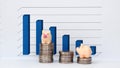 Business concept with miniature. TwoÃÂ smallÃÂ pinkÃÂ piggyÃÂ bankÃÂ onÃÂ theÃÂ stackÃÂ ofÃÂ coinsÃÂ inÃÂ frontÃÂ ofÃÂ theÃÂ graph. Royalty Free Stock Photo